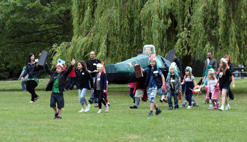 Families walk through a park, help to guide Uncle Lubin who is inside of a homemade submarine.