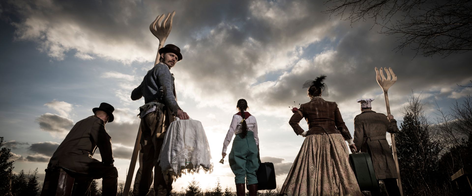 Promo image for Hunting of the Snark, The Banker, Isabelle, The Bonnet Maker, and The Baker look at into the sunset. Apart from The Butcher, holding a giant fork, faces us.