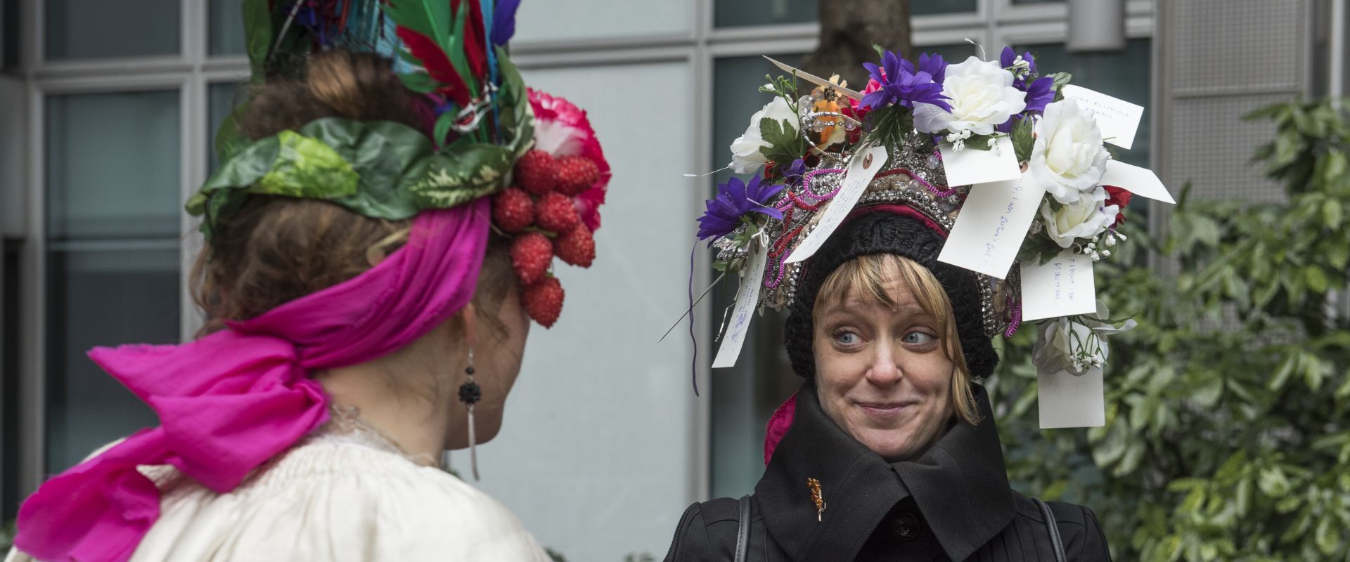 An audience member is wearing a headdress, and it is decorated with flowers and luggage labels.