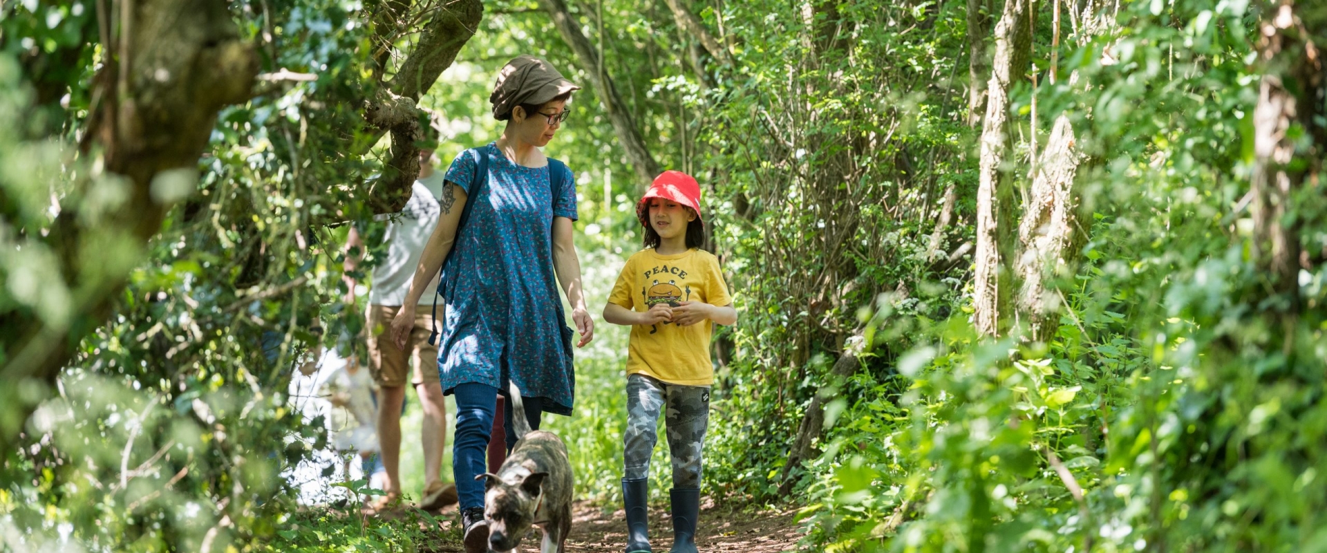 An adult and child ramble down a forest path.