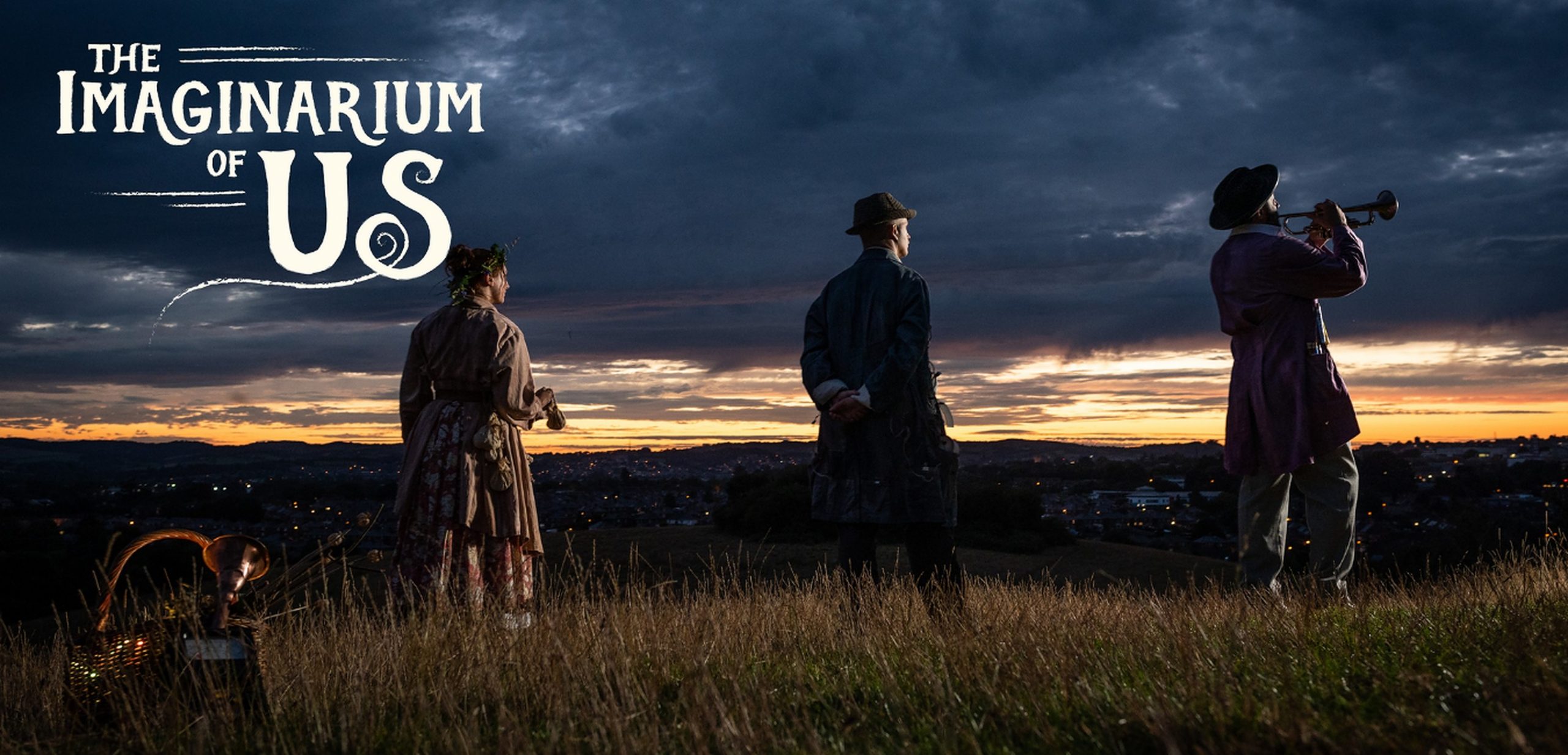 Imaginarium of Us promotion, photograph of three Curiositors; Mossy Grossy, Double Zero Three, and Ecolecuá in silhouette, backs to camera, watching the sunset on a hill side.